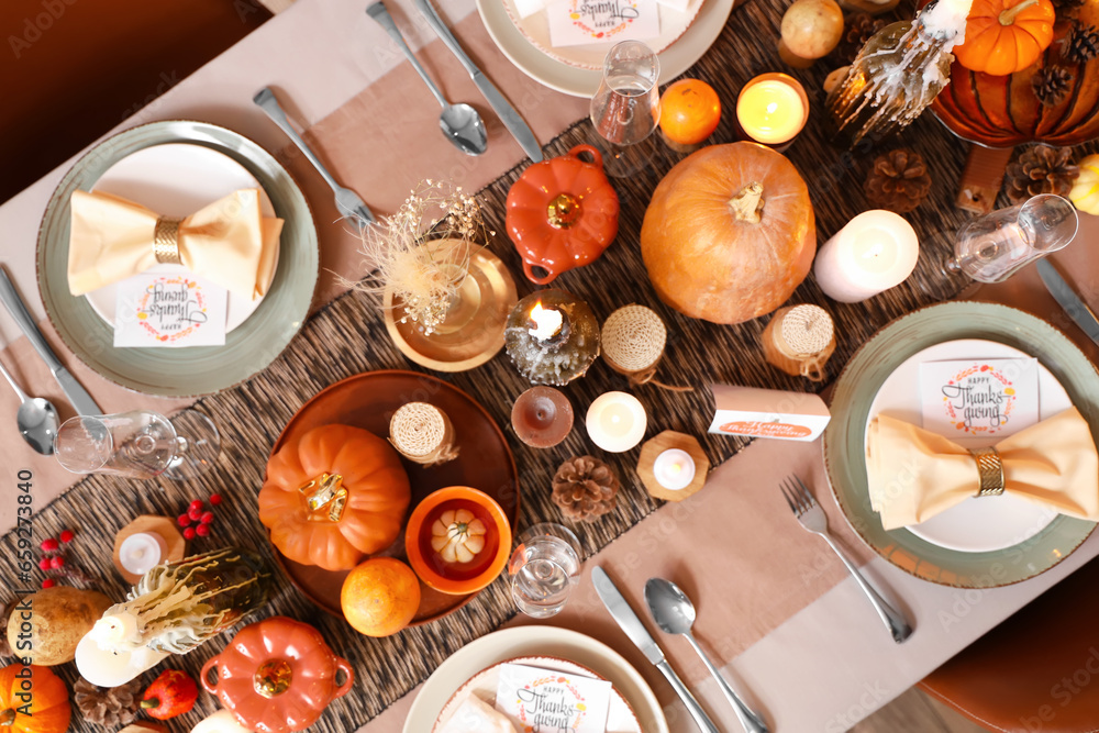 Beautiful table setting with burning candles, pumpkins and greeting cards for Thanksgiving dinner, top view