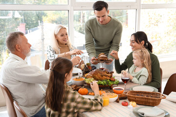 Happy family having dinner at festive table on Thanksgiving Day