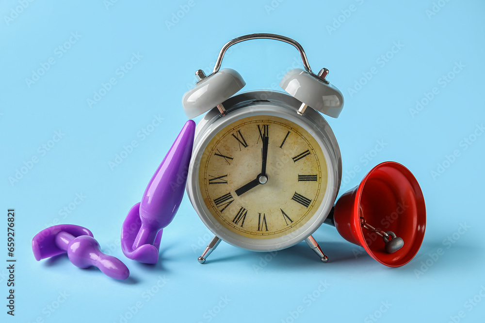 Alarm clock with anal plugs and bell on blue background. Time for sex