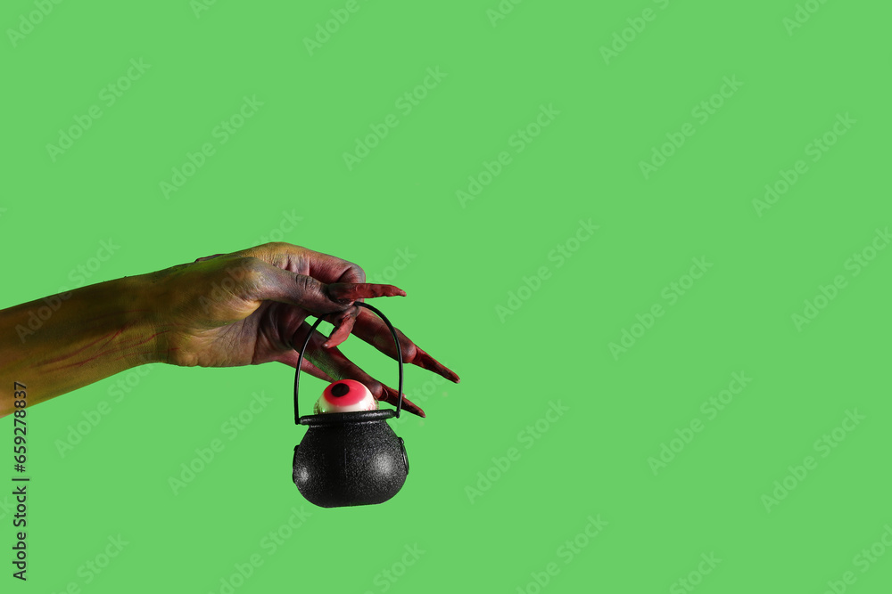 Witch with cauldron on green background. Halloween celebration