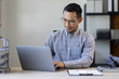 © David - Portrait of Stylish Asian Businessman Works on Laptop, Does Data Analysis and Creative Designer, Looks at Camera and Smiles. Digital Entrepreneur Works on e-Commerce Startup Project