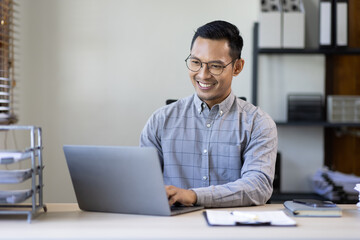 Wall Mural - Portrait of Stylish Asian Businessman Works on Laptop, Does Data Analysis and Creative Designer, Looks at Camera and Smiles. Digital Entrepreneur Works on e-Commerce Startup Project