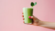 © PNG - Green smoothie in a glass in hand on a pink background