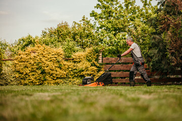 A senior man in a smart suit trims the hedges in his garden, demonstrating that a lifelong love for gardening never fades.