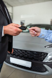 Fototapeta Zachód słońca - salesman give car key customer after success deal at modern showroom