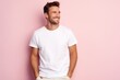 © radekcho - Portrait of a happy 30 - year - old man wearing a white t shirts with hands in pocket next to a light pink pastel background. Mock up t shirt concept.