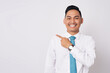 © Bangun Stock Photo - Portrait of a smiling happy young Asian man in formal wear standing pointing fingers aside at copy space for advertisement isolated on white background