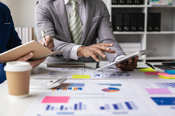 Close-up of a business team sitting at a desk in front of a laptop with a financial infographic and financial document of a startup company brainstorming a new project in a coffee shop.