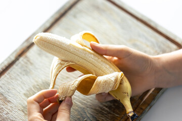 Wall Mural - A woman peels a ripe banana, close-up.