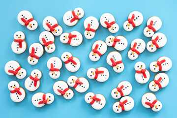 Wall Mural - Gingerbread snowmen covered with icing on a blue background, flat lay.