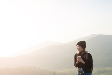 Wall Mural - woman traveler drinks coffee with view of mountain landscape. young tourist woman drinks hot drink from cup and enjoyed the scenery in mountains. trekking concept. concept adventure active vacations.