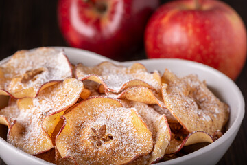 Wall Mural - in the foreground a bowl with slices of homemade dried apple flavored with icing sugar