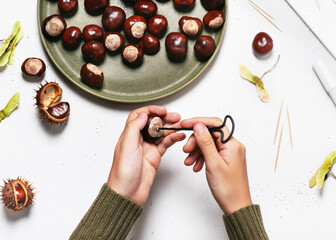 Child hands hold a hand drill tool and make a hole in the chestnut. Easy fun kids crafts concept. Step 2