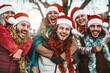 Happy friends wearing santa claus hat celebrating Christmas eve together - Young people having fun walking in Christmas market street - Winter holidays concept
