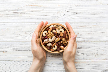Sticker - Woman hands holding a wooden bowl with mixed nuts Walnut, pistachios, almonds, hazelnuts and cashews. Healthy food and snack. Vegetarian snacks of different nuts