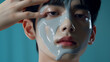© Cosmeticthingz - Handsome Korean Man Applying Serum in Front of Turquoise Background, Close-Up Shot, K-beauty. Magazine cover photo, cosmetics photo, beauty industry advertising photo.