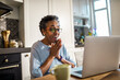 © Marko Geber - Senior African American woman using a laptop in the kitchen in her home