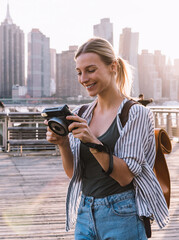 Wall Mural - happy woman with vintage equipment smiling at urban setting with Manhattan on background