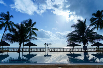 seaside resort swiming pool with silhoutted entrance against a clouded blue sky