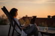 © olezzo - Young woman works on laptop on terrace above old town and sea