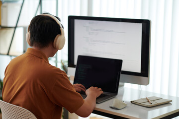 Developer wearing headphones when testing new software on laptop