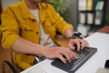 Wall Mural - Closeup image of man with disability working on computer in office, answering e-mails and coding