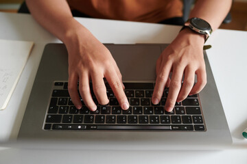 Hands of student coding or answering e-mails on laptop, view from above