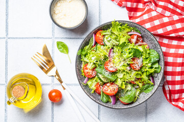 Wall Mural - Green vegetable salad with fresh leaves. Top view on white tile background.