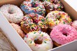 selective focus on glazed donuts with rainbow sprinkles in a paper box