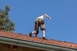A worker prepares the roof for the installation of solar panelss. the roof of a family house with red tiles,