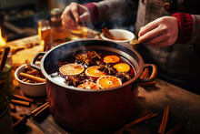 Woman Cooking Traditional Mulled Wine In Pot With Orange Slices And Spices Close-up
