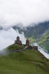 Wall Mural - A view of the iconic Trinity Church in Stepantsminda surrounded by low clouds