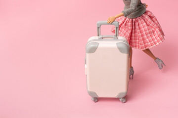 The doll carries a suitcase on wheels. Travel, vacation creative minimalistic concept