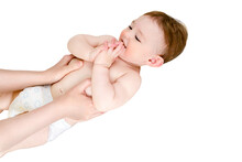 A Mother Gives A Belly Massage To A Toddler Baby Boy, Isolated On A White Background. Mom Hands Are Kneading The Child Body, Isolated On A White Background. Kid Aged One Year