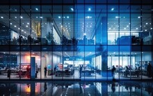 A Transparent Glass Office Building Brightly Lit With People Working Hard Inside