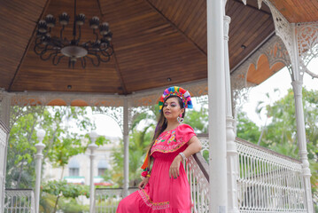 Wall Mural - Street portrait of Mexican woman wearing traditional dress with multicolored embroidery. Hispanic woman celebrating the day of the beginning of the Mexican Revolution.