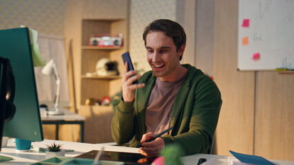 Wall Mural - Happy artist answering cellphone call drawing tablet close up. Man talking phone