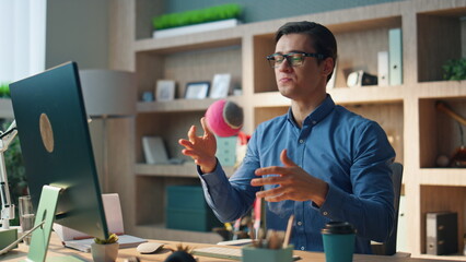 Wall Mural - Friendly freelancer videocalling computer at office. Smiling man gesturing hands