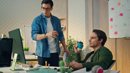 Wall Mural - Two creators discussing project sunny office. Focused freelancer drinking coffee