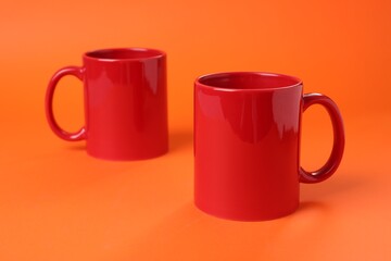 Poster - Two red ceramic mugs on orange background