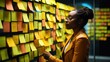 Web designer is working with brainstorming board full of sticky note from colleague	