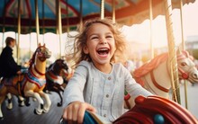 A happy child girl expressing excitement while having fun on a merry-go-round colorful carousel at an amusement park