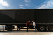 © phoenix021 - Father and son together starting trucking business, shaking hands in front of long hail truck with trailer