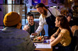 © Marko Geber - Young Caucasian waiter serving sushi to a diverse group of friends in a sushi restaurant