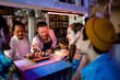 © Marko Geber - Young sushi chefs presenting a plate of sushi to a group of diverse friends in a sushi restaurant or bar