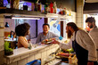 © Marko Geber - Young sushi chef serving sushi to a diverse couple in a sushi restaurant or bar