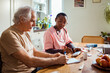 © Marko Geber - Young African American caregiver going over medication with her senior male patient at his home