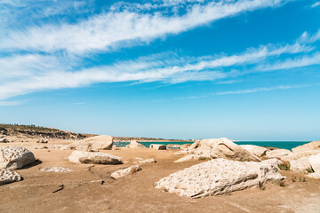 Wall Mural - Fragments of ancient rocks on sandy beach. Sea shallowing