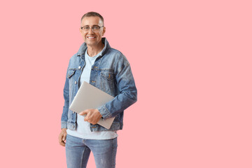 Wall Mural - Mature male programmer with laptop on pink background