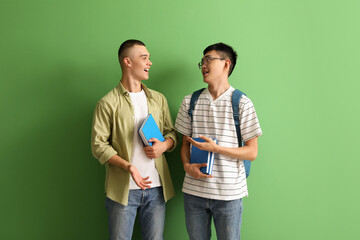 Canvas Print - Happy male students with books on green background